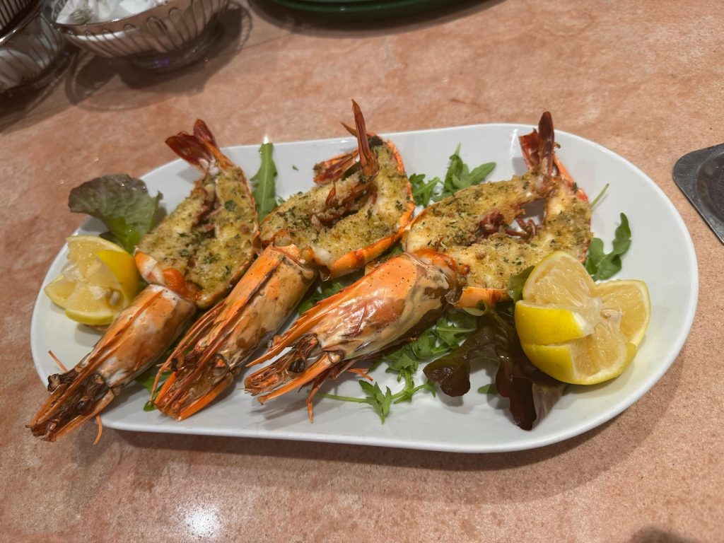 Knusprig gratinierte Riesen-Gambas auf Rucola mit frischer Zitrone im Restaurant Roma