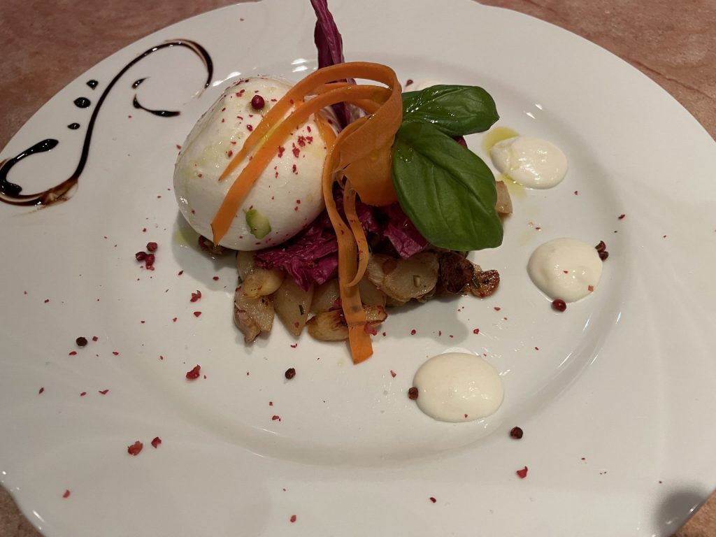 Cremige Burrata serviert auf einem Bett aus gebratenen Auberginen mit Kirschtomaten und Basilikum im Restaurant Roma